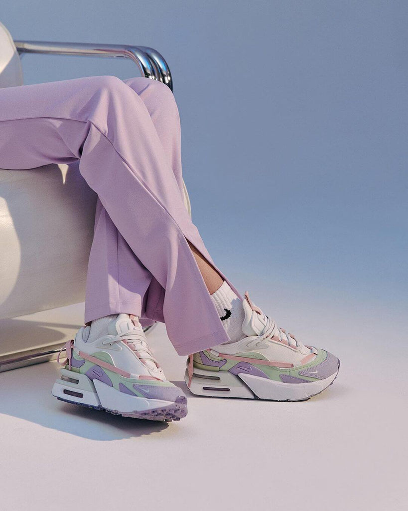 Person wearing pastel-colored Nike sneakers and lilac pants, showcasing athleisure fashion trend.
